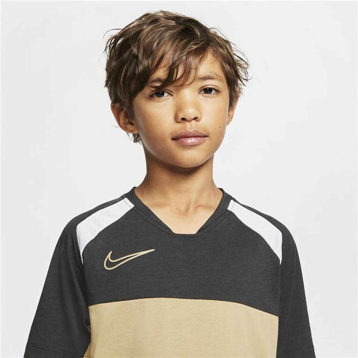 Young boy wearing black and beige Nike sports jersey with white shoulder accents on white background