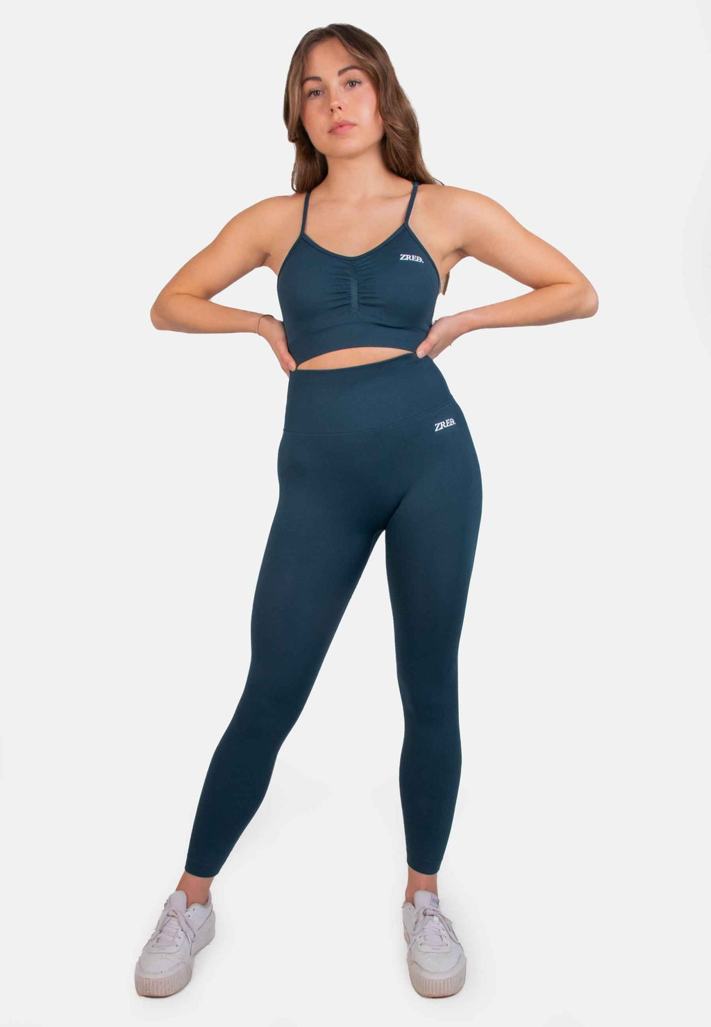 Model wearing Shape Seamless Sports Bra with teal high-waisted leggings, featuring adjustable straps and removable pads.