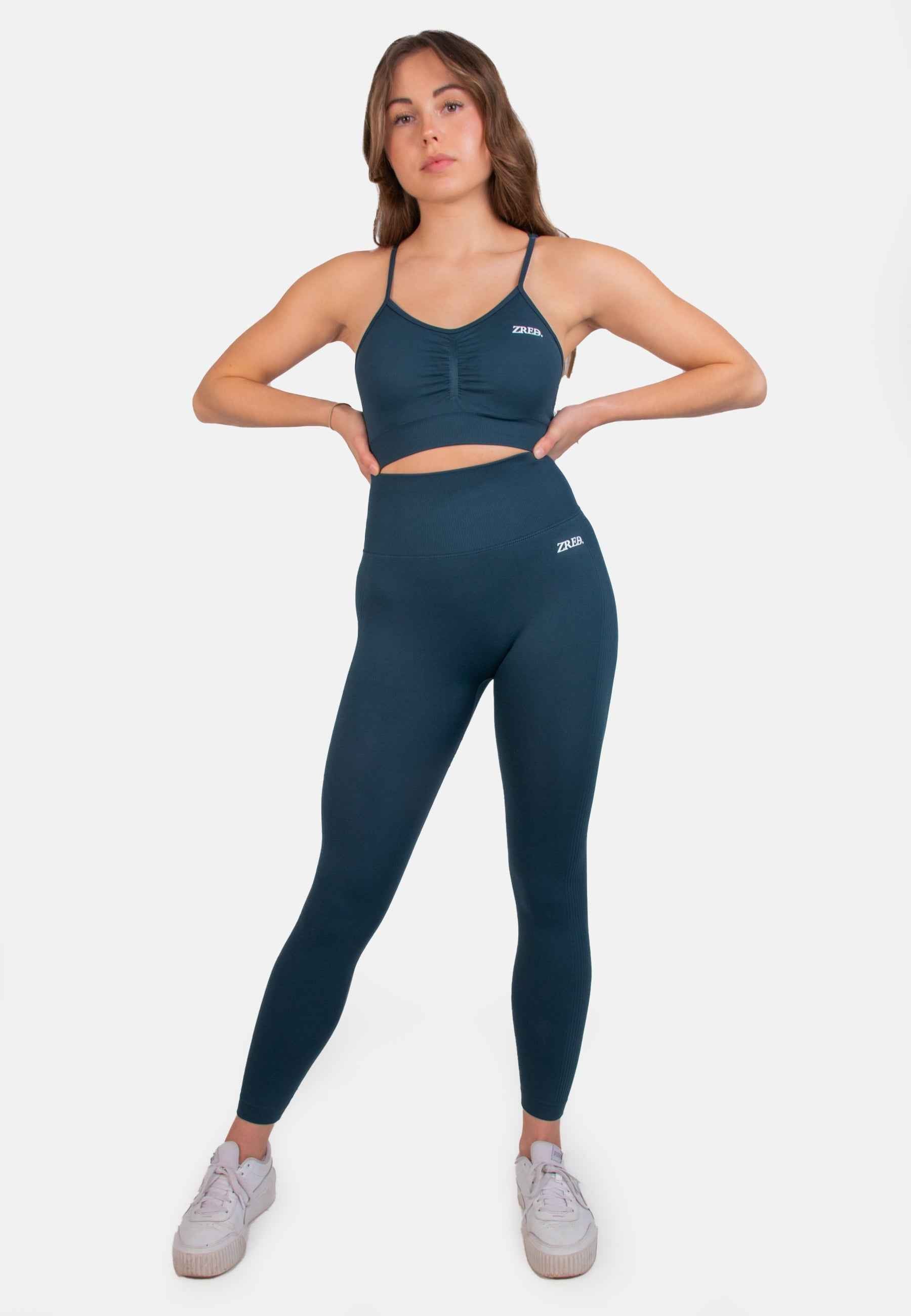 Model wearing Shape Seamless Sports Bra with teal high-waisted leggings, featuring adjustable straps and removable pads.