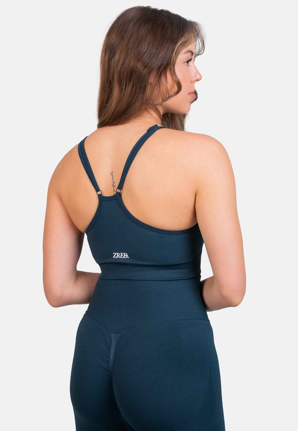 Shape Seamless Sports Bra back view in deep teal with adjustable straps and logo.